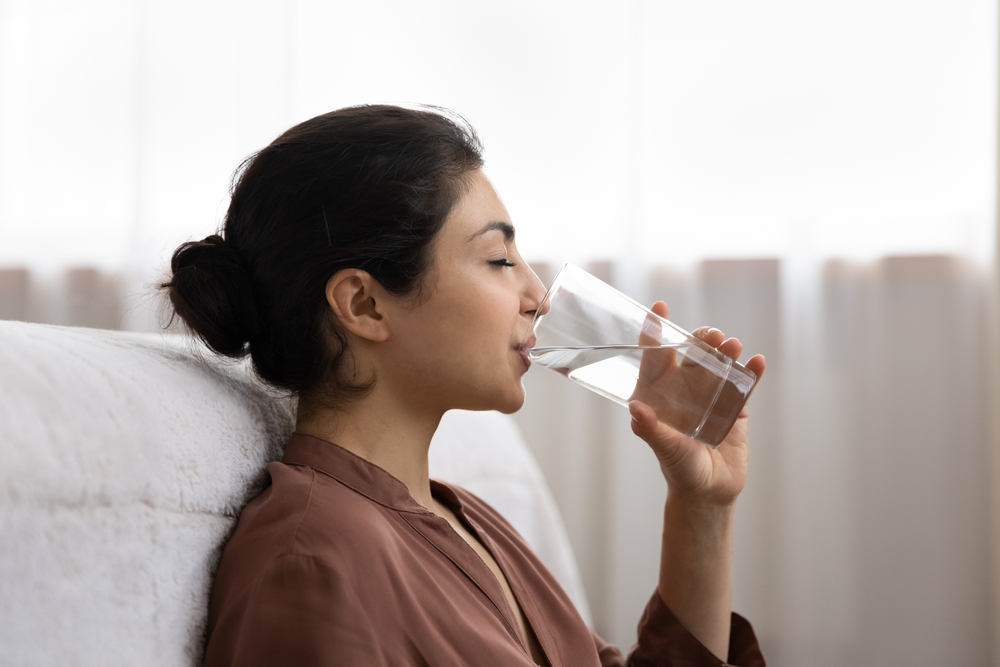 Woman drinking water to stay hydrated after bariatric surgery.