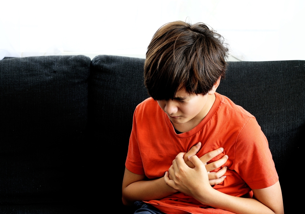 Child holding their chest, experiencing discomfort from musculoskeletal chest pain.